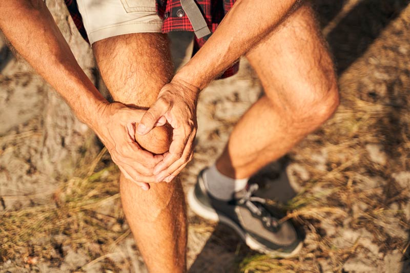man suffering pain in knee in nature