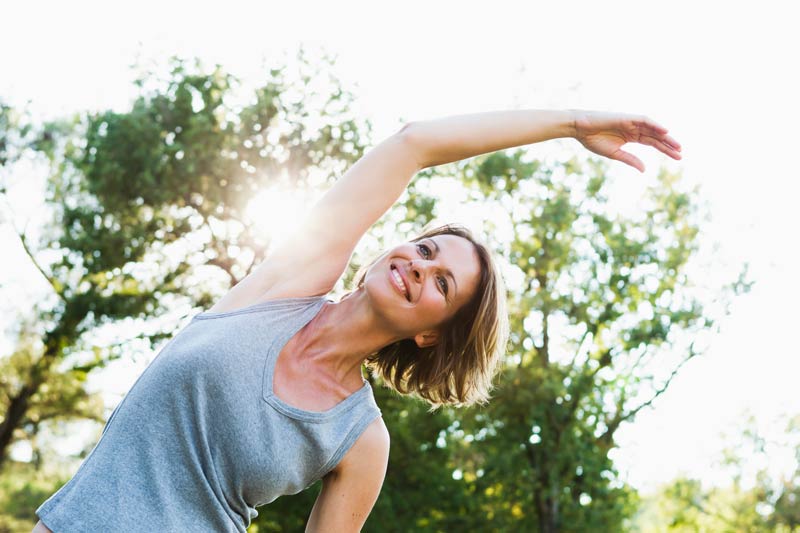 smiling woman stretching outdoors