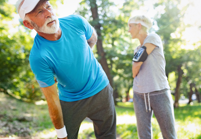 Older Man Holding Back While Jogging Outdoors